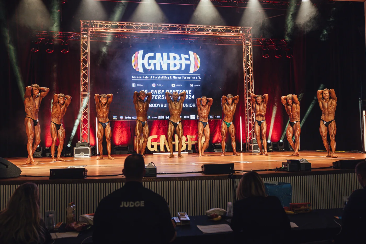 Bodybuilding-Wettkampfbühne mit Athleten beim Posing vor der Jury.