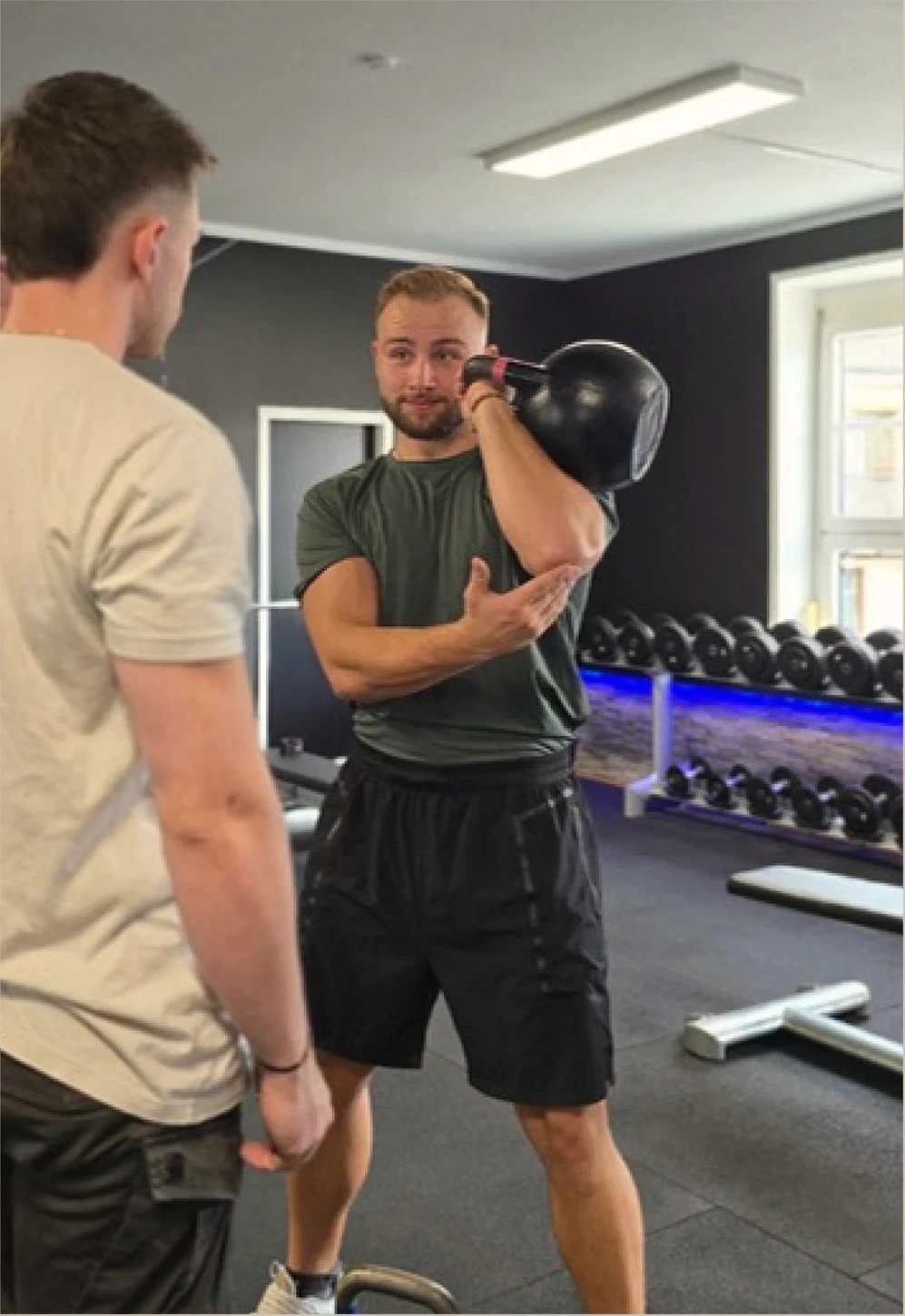 Toni demonstriert im persönlichen Coaching eine Kettlebell-Übung.